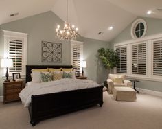 a bedroom with a large bed and chandelier hanging from the ceiling