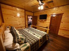 a bed in a room with wooden walls and ceiling fans on either side of the bed