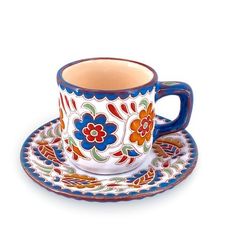 a cup and saucer decorated with colorful flowers on a white background, sitting next to each other