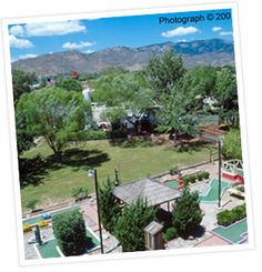 an aerial view of a tennis court in the middle of a park with mountains in the background