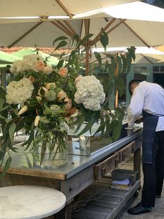 a man standing next to a table with flowers in it