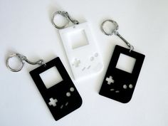 two black and white gameboy keychains sitting next to each other