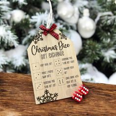 a wooden christmas gift exchangeer with red dices sitting on a table in front of a tree