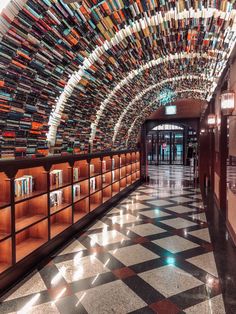 a long hallway with many books on the wall and tiled flooring in front of it