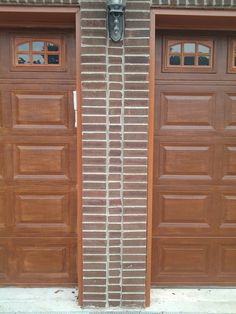 two brown garage doors are open on the side of a brick building