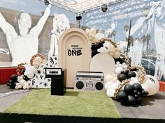 an outdoor stage with balloons, speakers and decorations on the grass in front of it