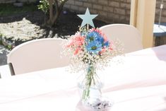 a vase filled with flowers sitting on top of a table next to a white chair