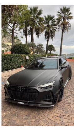 a black car parked in front of some palm trees