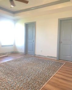 an empty room with two doors and a rug on the floor