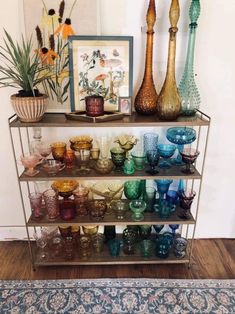 a shelf filled with vases and bowls on top of a wooden floor next to a painting