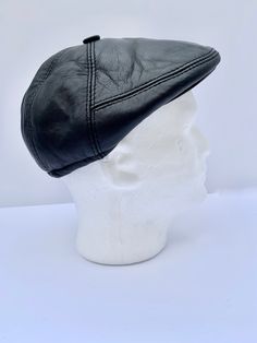 a white mannequin head wearing a black leather hat