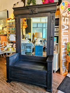 an antique looking mirror sitting on top of a wooden shelf in a store filled with furniture