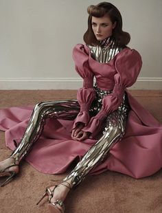 a woman sitting on the floor in pink and silver clothes with her legs spread out