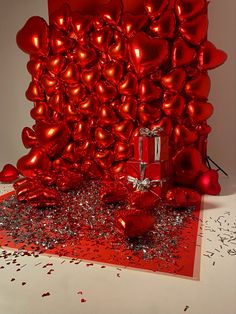 a red gift box surrounded by hearts and confetti