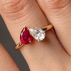 a woman's engagement ring with two pear shaped ruby and diamond stones on it