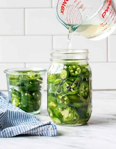 a mason jar filled with pickled cucumbers next to a blue and white towel