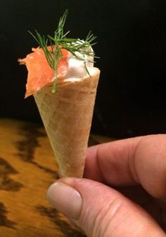 a person is holding up a small cone with food in it's center and garnishes on top