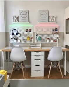 two white chairs sitting at a desk in front of a wall with pegboards on it