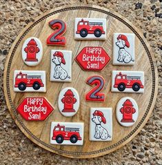 a wooden plate topped with cookies decorated like firetrucks and trucks on top of a stone floor