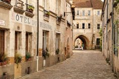 an alley way with old buildings and people walking down the street in front of it