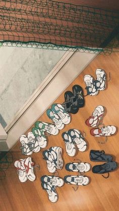 there are many pairs of shoes on the floor next to a door and net behind them