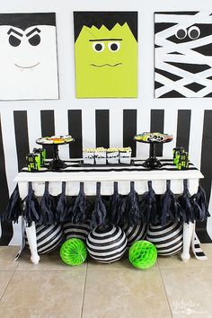 the table is decorated with black and white striped paper decorations, green tissue pom poms, and monster faces