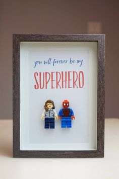 a lego man and woman are in a shadow box with the words, you will forever be my superhero