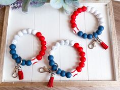 two bracelets with red, white and blue beads are sitting in a wooden box