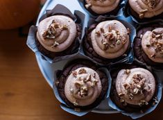 chocolate cupcakes with frosting and pecans in paper cups on a plate