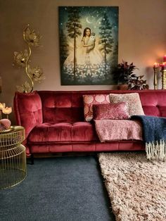 a living room with a red couch, rug and painting on the wall behind it