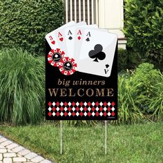 a lawn sign that says, big winners welcome with four playing cards on it in front of some bushes