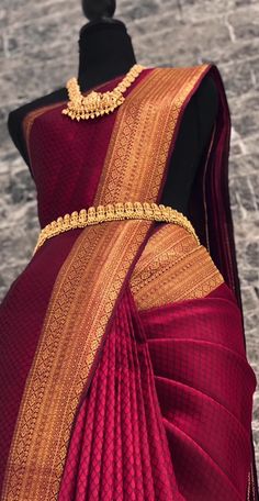 a red and gold colored saree on display in front of a mannequin