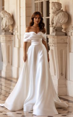 a woman in a white wedding dress standing on a tile floor with her hand on her hip