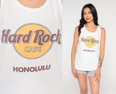 "Vintage 80s tank top from the Hard Rock Cafe in Honolulu. Please see measurements and condition below. Every garment we sell is authentic vintage and one-of-a-kind! You will receive the exact item photographed. Condition: Has a couple small pinholes, see photos Best fits women's: Small Material: Feels like Cotton MEASUREMENTS Taken from seam to seam while the garment is lying flat. Double the armpit, waist, and hips For reference, model is 5'6\" and measures 32-26-37. Length from Top: 25\" Armp White Rock And Roll Top For Summer, Casual Sleeveless Tank Top For Music Festival, Rock And Roll Style Tops For Summer Music Festival, White Rock And Roll Tops For Summer, Casual Tank Top For Music Festival, Sleeveless T-shirt For Summer Concerts, White Rock And Roll Summer Tops, Y2k Sleeveless Top For Music Festival, White Rock And Roll Summer Top