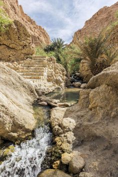 there is a small waterfall in the middle of some rocks and water flowing down it