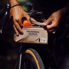 a person is holding a bag on the back of a bike with an orange tube in it