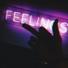 a person holding their hand up in front of a neon sign that reads, feelings