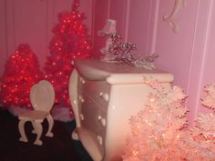 a pink christmas tree next to a white dresser and baby's chair in a room