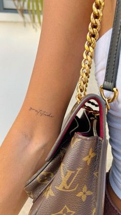 a close up of a person's arm with a small tattoo on her wrist