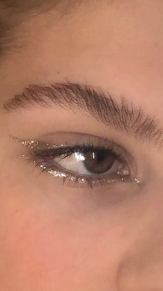 a woman's eye with shiny lashes and gold glitter on the bottom half of her eyelashes