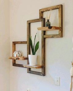 two wooden shelves with plants on them in a corner next to a wall mounted mirror