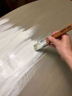 a person is using a brush to paint a table