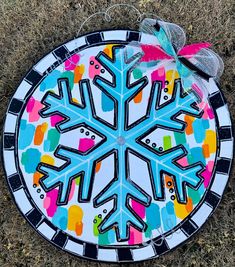 a painted snowflake sitting on the ground with a bow around it's neck