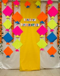 colorful paper decorations are on display in front of a yellow backdrop that says happy sankish