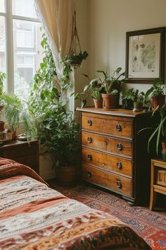 a bedroom with lots of plants in the window sill and dresser next to it