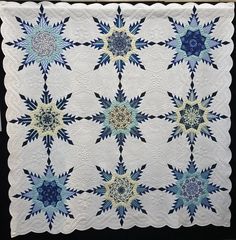 a white quilt with blue and green stars on the front, along with black background