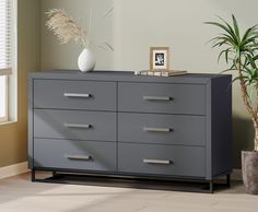 a gray dresser in a room with a potted plant