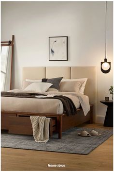 a bed sitting on top of a wooden floor next to a wall mounted light fixture