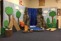 an indoor play area with trees, rocks and water fall on the wall next to it