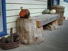 some pumpkins and gourds are sitting on a wooden bench next to a house